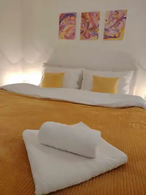 two beds with white sheets and yellow pillows at AGAPE in Leskovac
