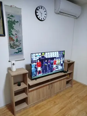 a flat screen tv sitting on a wooden entertainment center with a clock at Apartman NINASTA in Pirot
