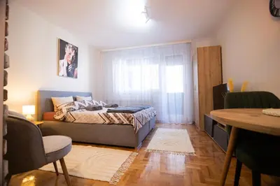 a bedroom with a bed and a table and a window at Studio Iris 2 in Niš