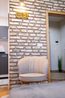 a chair sitting in front of a brick wall at Studio Iris 2 in Niš