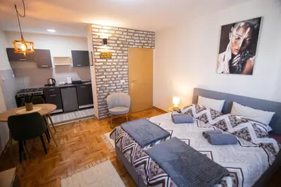 a bedroom with a large bed and a kitchen at Studio Iris 2 in Niš
