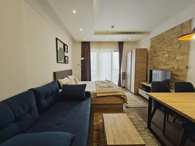 a living room with a blue couch and a bed at Studio Ristic Milmari L5 in Kopaonik