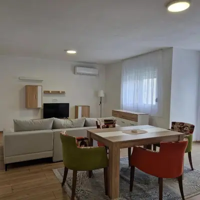 a living room with a couch and a table and chairs at Apartman Milos - centar grada free parking in Vranje