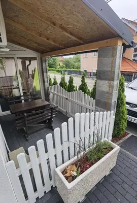 a white picket fence on a porch with a bench at Apartman VRH in Vrnjačka Banja