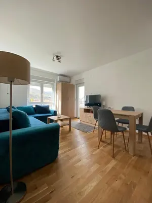 a living room with a blue couch and a table at Apartman Sky view - Sokobanja in Soko Banja