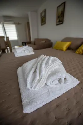 a pile of white towels on a bed at Apartmani Rosica in Ribarska Banja