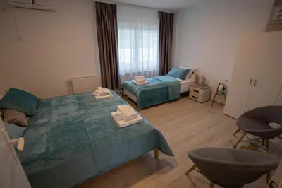 a bedroom with two beds and a chair in it at Apartmani Rosica in Ribarska Banja