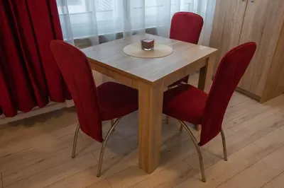 a wooden table with red chairs and a cup on it at Apartmani Rosica in Ribarska Banja