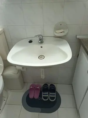 a bathroom with a sink and two pairs of shoes under it at Apartmani Jelena in Vrnjačka Banja