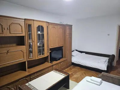 a room with wooden cabinets and a bed and a tv at Apartman NINA in Kuršumlija