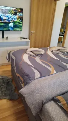 a bed in a room with a tv on a wall at Apartman ARMANE 4 star LUX & Free EVcharge in Vrnjačka Banja