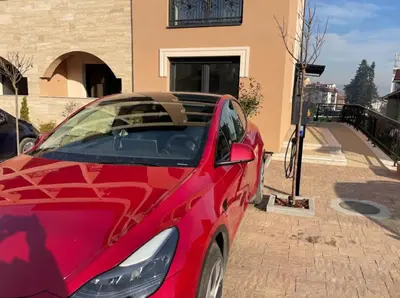 a red car parked in front of a house at Apartman ARMANE 4 star LUX & Free EVcharge in Vrnjačka Banja