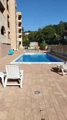 a swimming pool with two lounge chairs next to a building at Apartman ARMANE 4 star LUX & Free EVcharge in Vrnjačka Banja