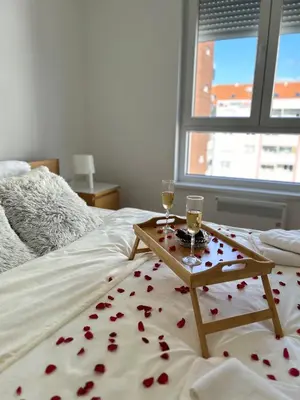 a table with two glasses of wine on a bed at Sunset in Niš