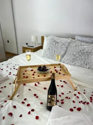 a tray with a bottle of wine and two glasses on a bed at Sunset in Niš