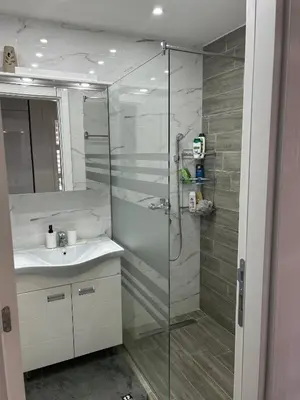 a bathroom with a glass shower and a sink at Sunset in Niš