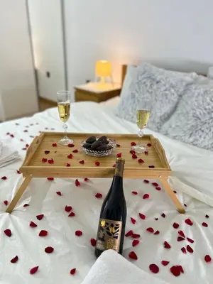 a tray with a bottle of wine and two glasses on a bed at Sunset in Niš