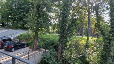a car parked in a parking lot next to trees at PREMIUM APARTMAN ELENI ROOMS,oaza mira i tisine u centru Vrnjacke banje in Vrnjačka Banja