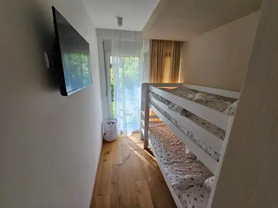 a bedroom with two bunk beds and a flat screen tv at PREMIUM APARTMAN ELENI ROOMS,oaza mira i tisine u centru Vrnjacke banje in Vrnjačka Banja