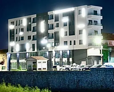 a large white building with cars parked in front of it at Riverside Nis in Niš
