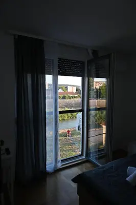 a bedroom with a large window with a view of the water at Riverside Nis in Niš