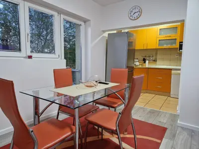 a kitchen with a glass table and orange chairs at Apartment F.R.I.E.N.D.S in Paraćin