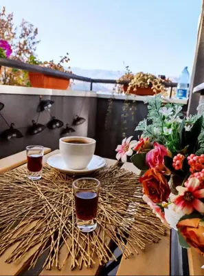 a table with two glasses of coffee and flowers on a balcony at BlueSky in Vrnjačka Banja