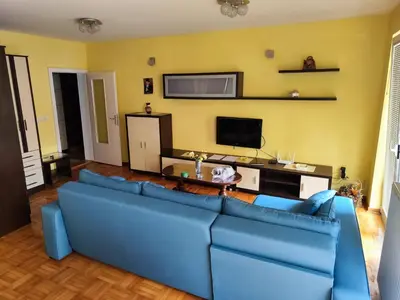 a living room with a blue couch and a tv at Apartman Leone Vrnjačka Banja in Vrnjačka Banja