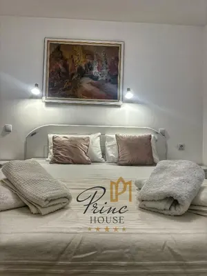 a bedroom with a large bed with a picture on the wall at Princ house in Leskovac