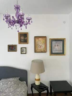 a bedroom with a purple chandelier and pictures on the wall at Vrnjacka Renesansa Promenada in Vrnjačka Banja