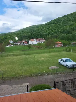 a car parked in a field next to a hill at Apartment Pavlović in Soko Banja