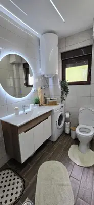 a bathroom with a toilet and a sink and a washing machine at Apartman Tina in Soko Banja