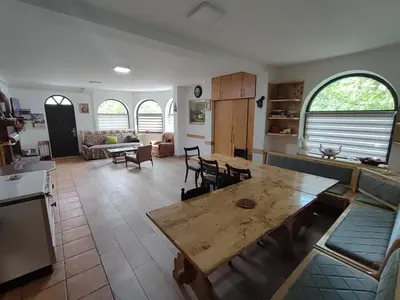 a kitchen and a living room with a wooden table at Kuca za odmor Lisine in Despotovac
