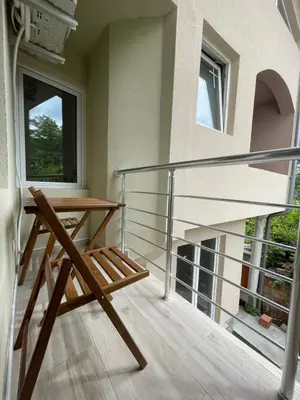 a balcony with a wooden table and a glass railing at Apartmani Videnovic Sokobanja in Soko Banja