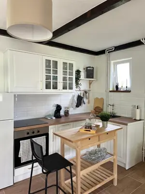 a kitchen with white cabinets and a wooden table at Villa Buena in Despotovac