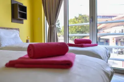 two beds with red towels on them in a room with a window at Studio Apartman Ad fines in Kuršumlija