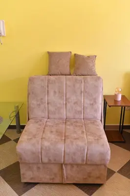 a brown couch in a room with a yellow wall at Studio Apartman Ad fines in Kuršumlija