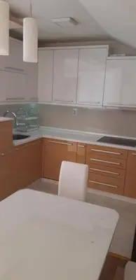 a kitchen with white cabinets and a table and chairs at Apartman Nina in Vranje