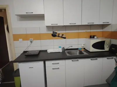 a kitchen with white cabinets and a sink and a microwave at Nena Studio in Jagodina
