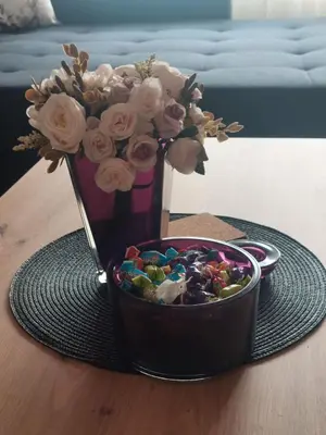 a vase with flowers and a bowl of candy at Balkan HOME in Kalna