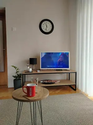 a living room with a tv and a clock on the wall at Balkan HOME in Kalna