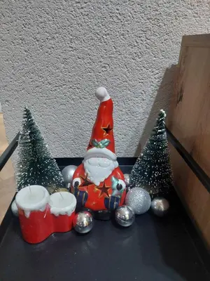 a santa claus figurine sitting between two christmas trees at Balkan HOME in Kalna