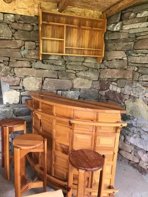 a wooden bar with stools and a stone wall at Apartmani Nikola Dojkinci in Pirot