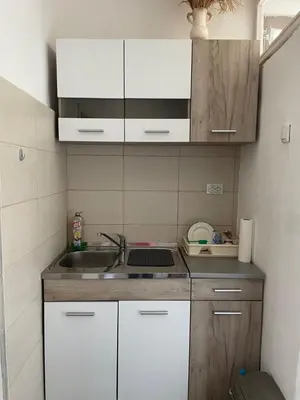 a small kitchen with white cabinets and a sink at Apartmani Nikola Dojkinci in Pirot