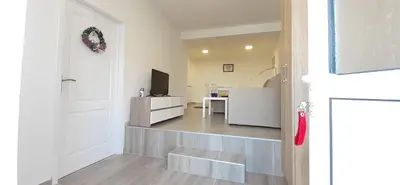 a hallway with a door and a living room with a table at Apartments Villa Stars in Kopaonik