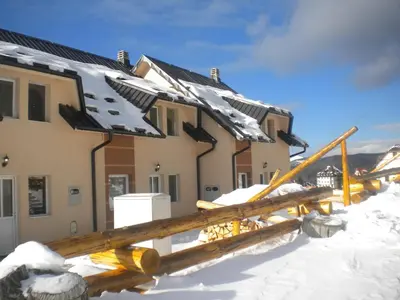 a house covered in snow with a wooden fence at Apartments Villa Stars in Kopaonik