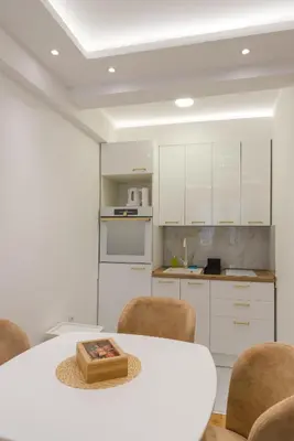 a white kitchen with a white table and chairs at Apartmani Central 14 & Free parking garage in Vrnjačka Banja