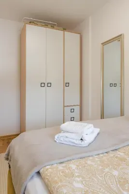 a bedroom with a bed with two closets and two mirrors at Apartmani Central 14 & Free parking garage in Vrnjačka Banja