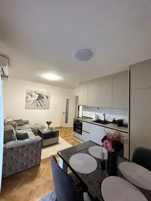 a kitchen and a living room with a table and chairs at Talija apartman 3 in Vrnjačka Banja