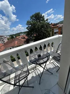 a balcony with chairs and a glass table on a balcony at Apartman Daria in Vrnjačka Banja